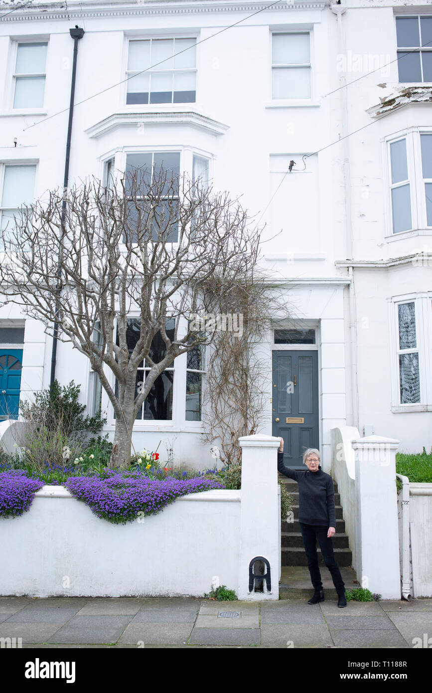 A female brighton home owner stands in front of her Georgian terraced house. Stock Photo
