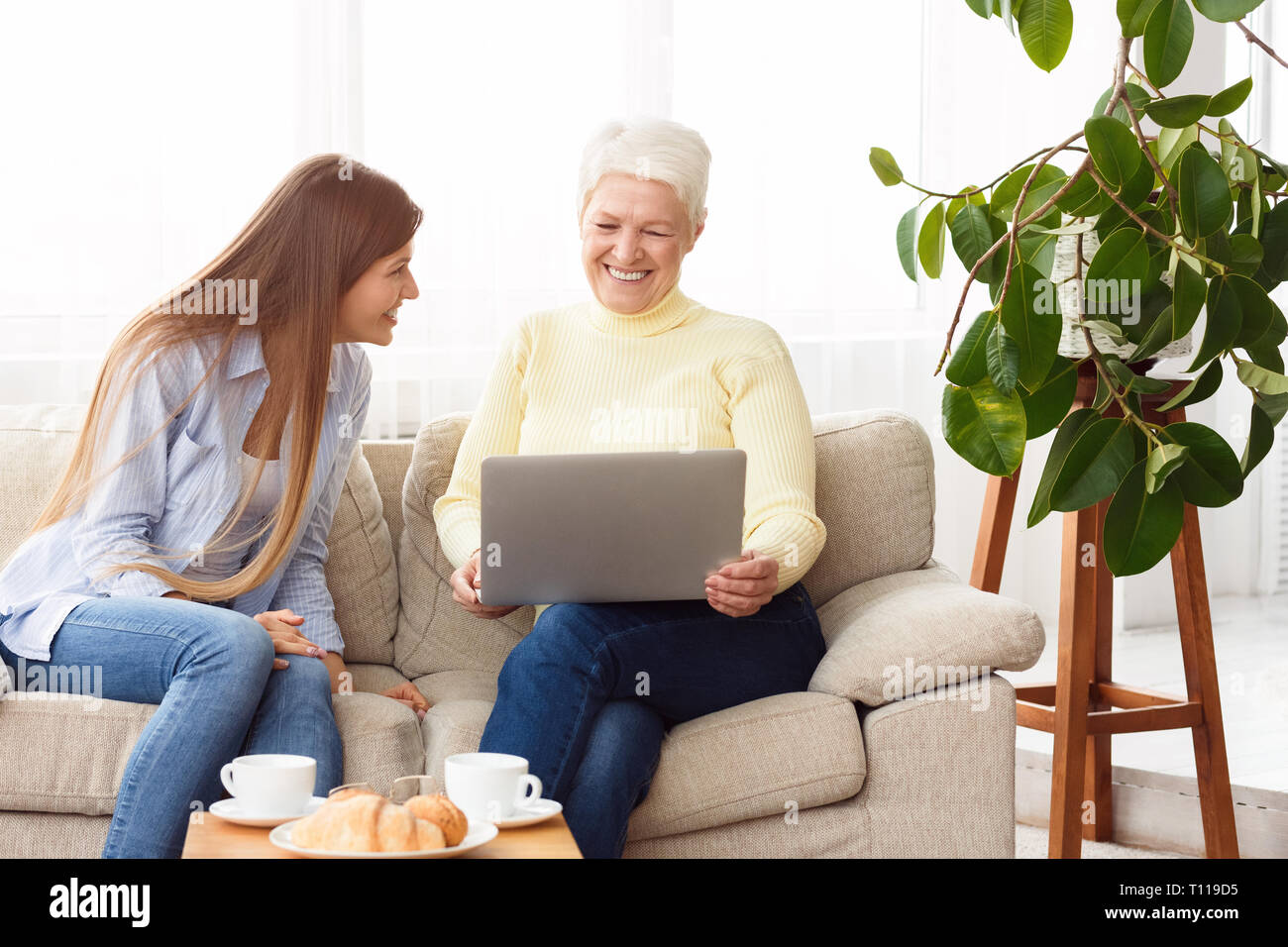 Laughing mother and daughter watching videos on laptop Stock Photo