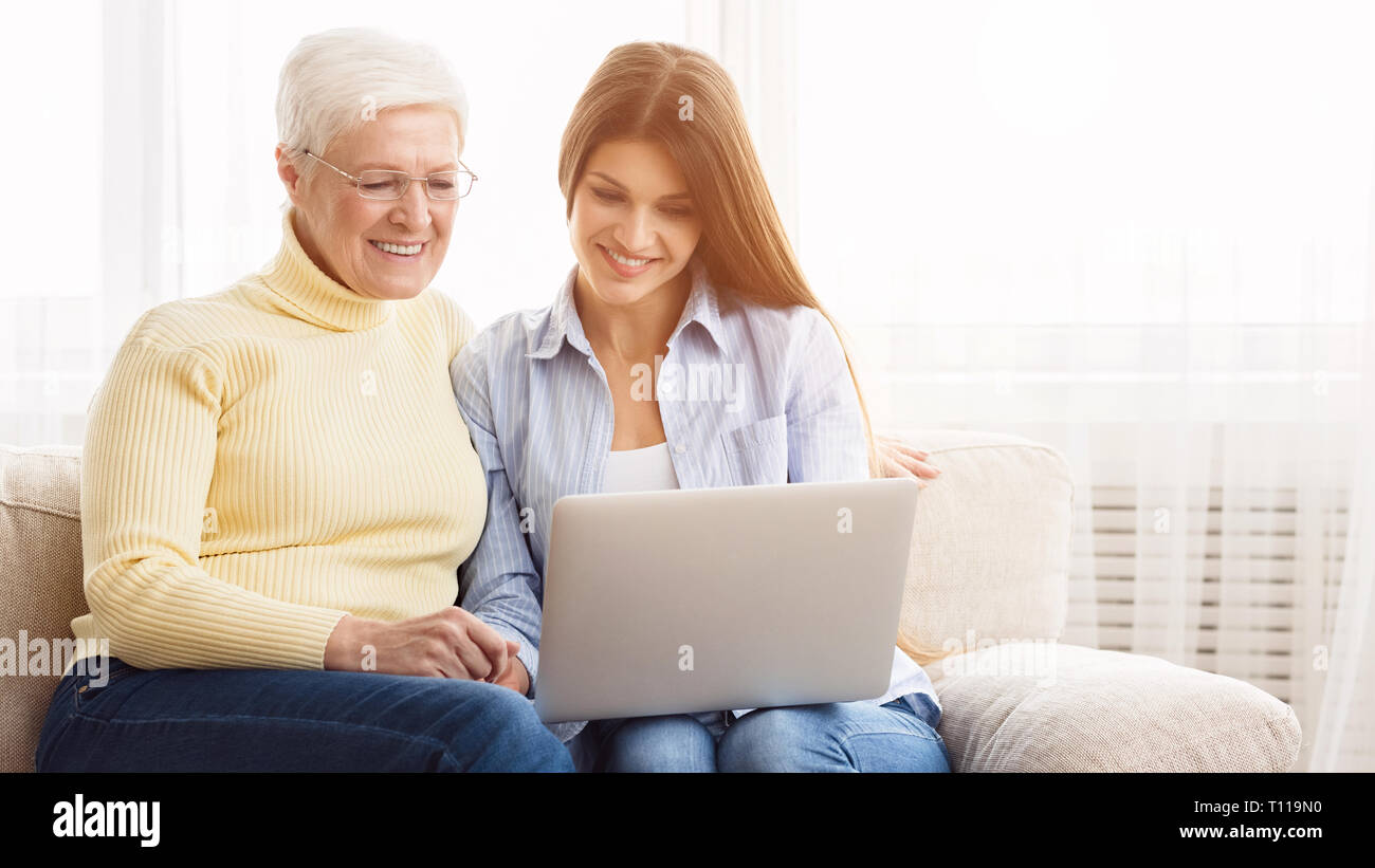 Daughter and mother surfing internet on laptop Stock Photo