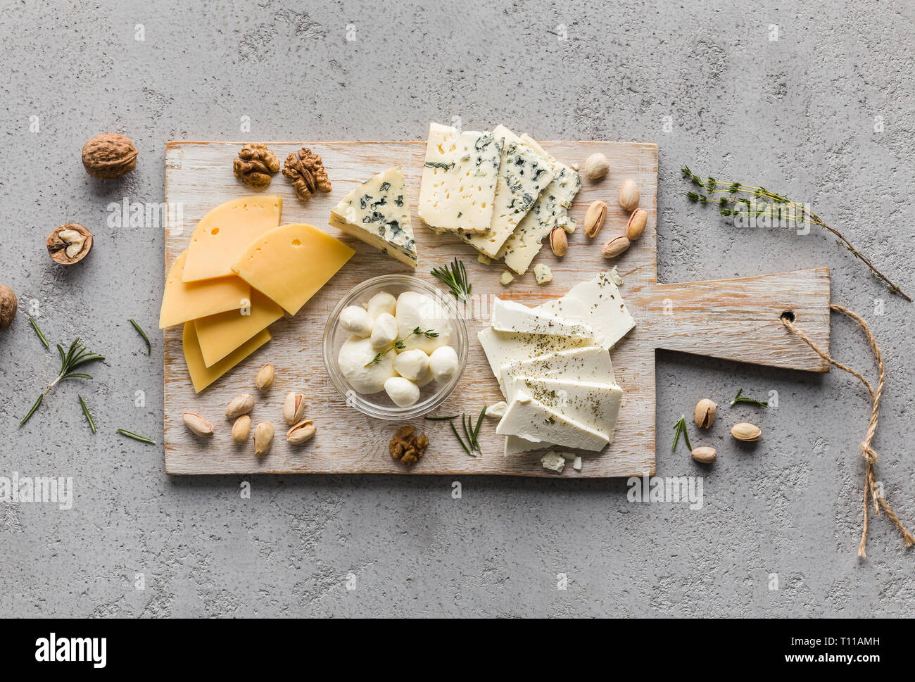 Assortment of cheese with nuts on wooden board Stock Photo