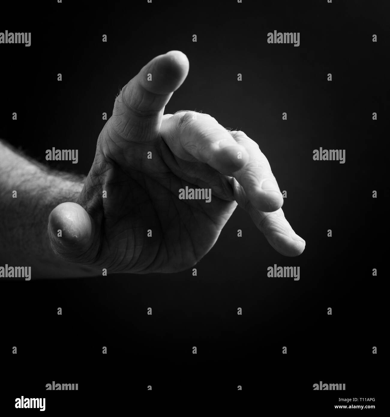 Black & white image of man`s hand pointing, isolated against a black ...