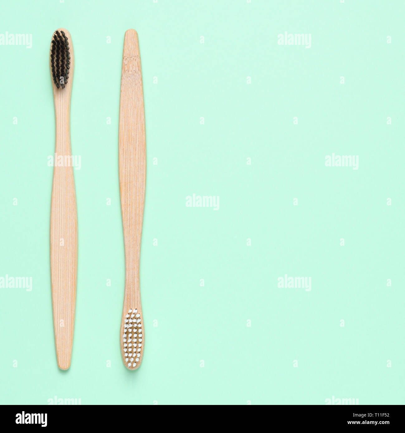 Bamboo toothbrushes on light green background with text space Stock Photo