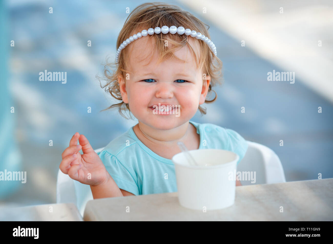 Adorable little girl eating ice cream at outdoor cafe on beautiful summer day Stock Photo