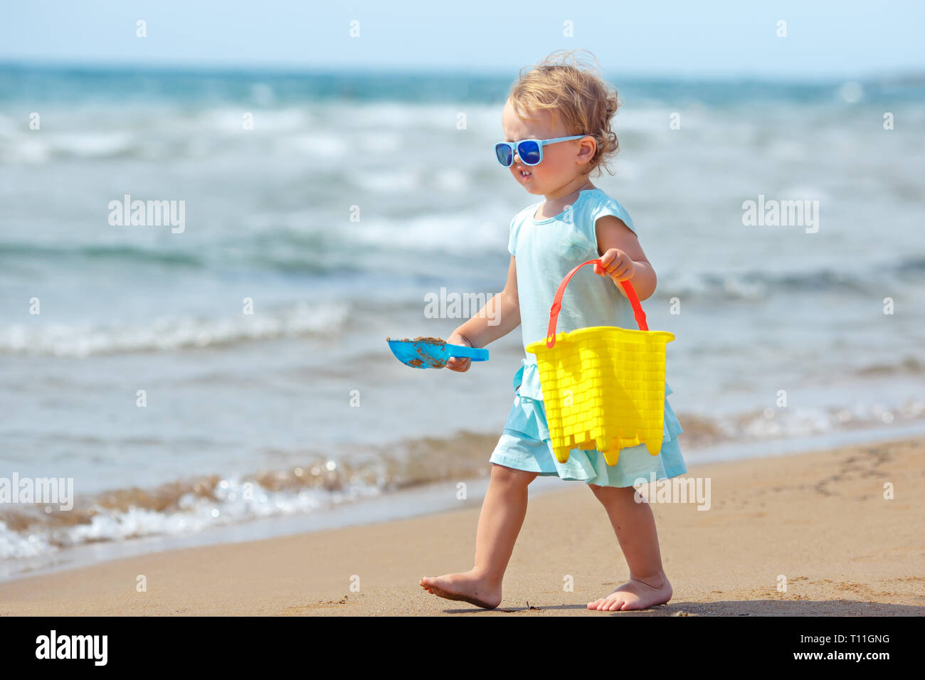 Child playing on tropical beach. Little girl digging sand at sea shore. Family summer vacation. Kids play with sand toys. Travel with young children Stock Photo