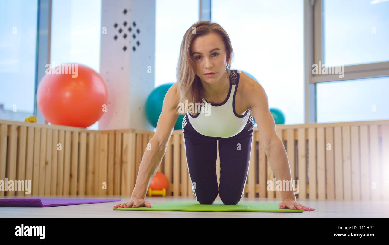 Young woman fitness trainer doing push ups in the studio Stock Photo