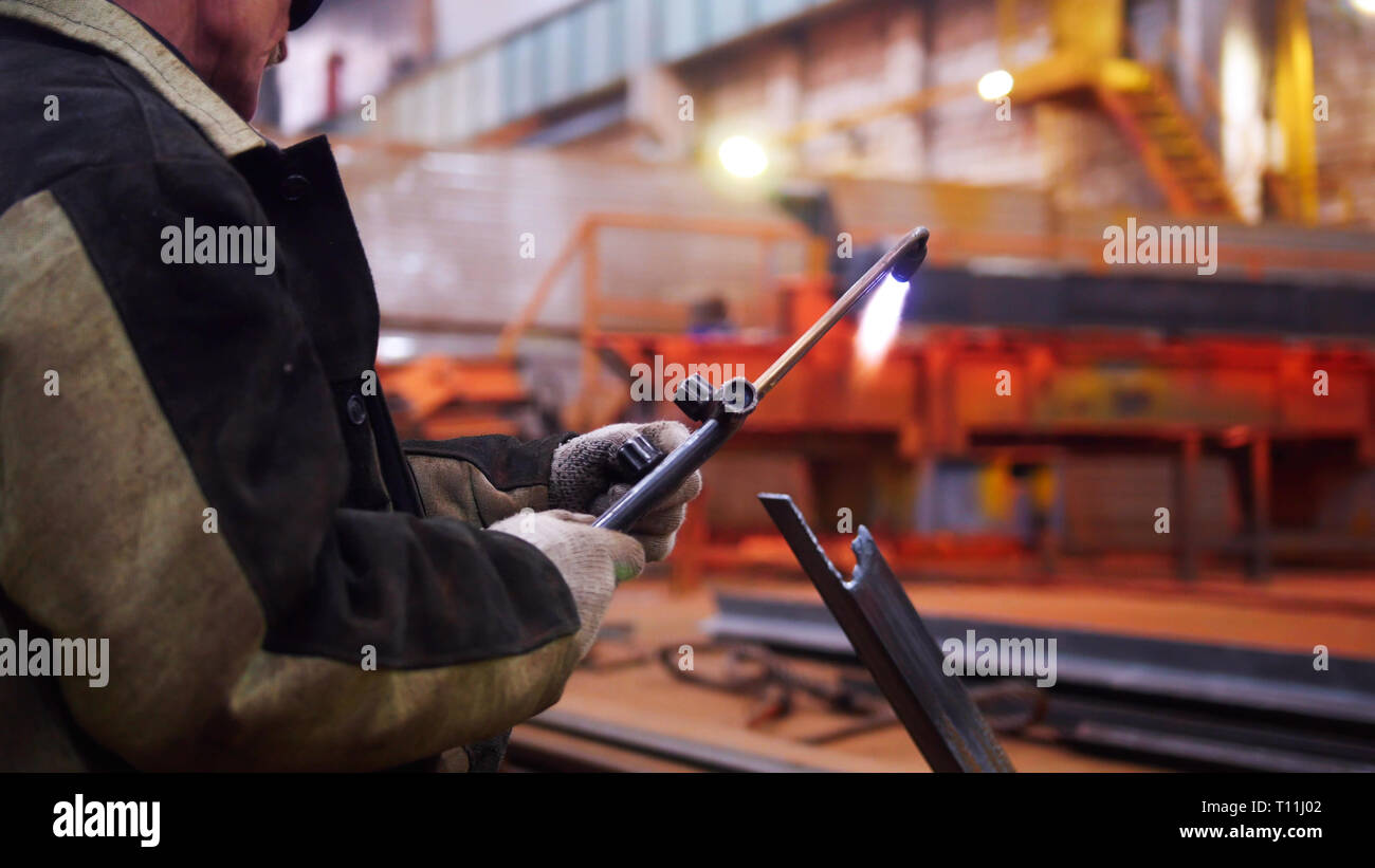Construction plant. A worker holding a gasburner Stock Photo Alamy