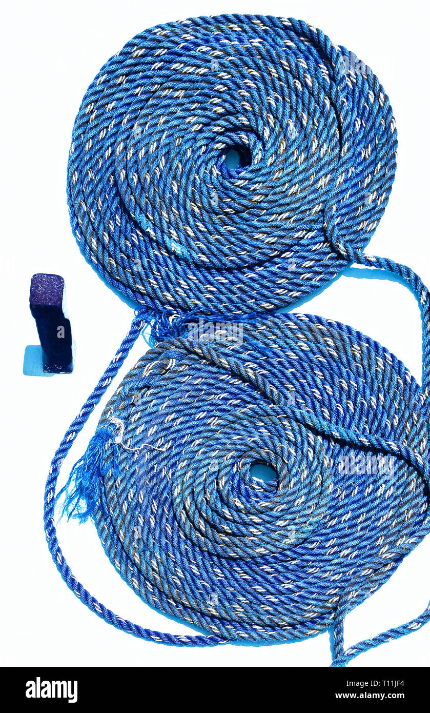 Blue colored maritime rope orderly coiled up in two rolls photographed against a white background on a ship in the Philippines Stock Photo