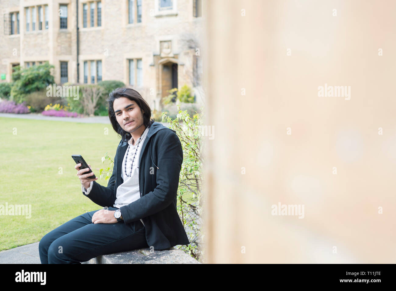 A confident male Middle Eastern international student in the square of an oxbridge college Stock Photo