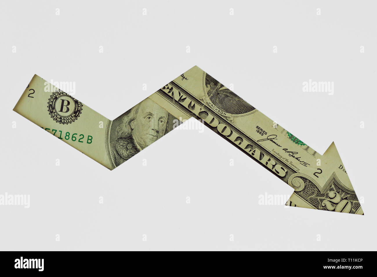 Downward arrow made of dollar banknotes on white background - Concept of downward trend of dollar currency Stock Photo