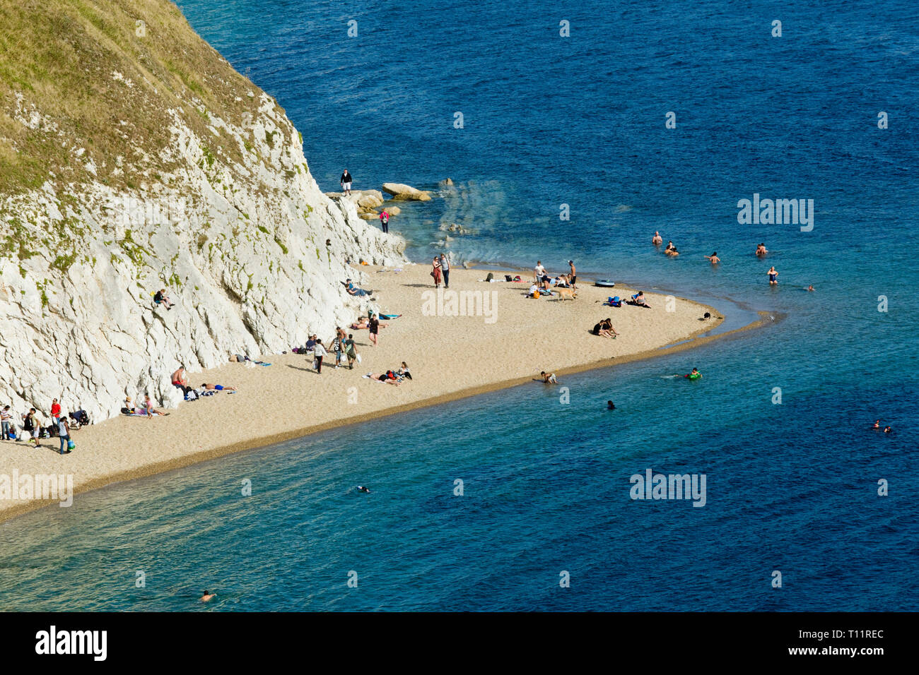 Great Britain, Dorset, Durdle Dor.  Torquoise sea and holiday makers relax at an idyllic beach. Stock Photo