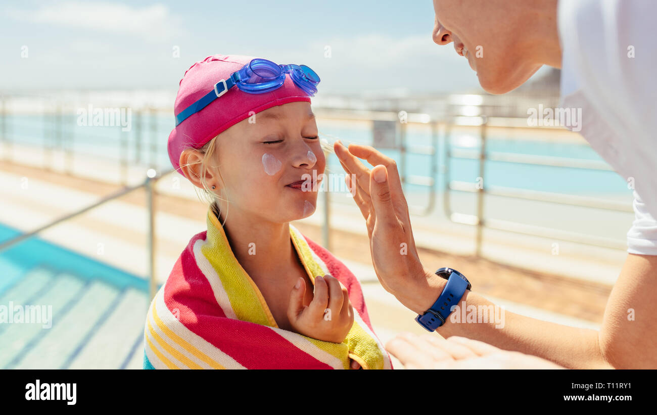Woman applying cream on the cafe of girl wrapped in towel after