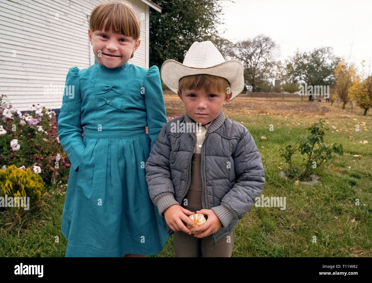 A young sister and brother pose outdoors on their family farm in a Mennonite community in the state of Chihuahua in northwestern Mexico. The Mennonites in Chihuahua are descendants of 16th-century Swiss Anabaptists who moved to Canada in the late 1800s to avoid persecution for their beliefs. In the 1920s, those Mennonites moved on south to Mexico, where as many as 100,000 live today in various parts of the country. Stock Photo