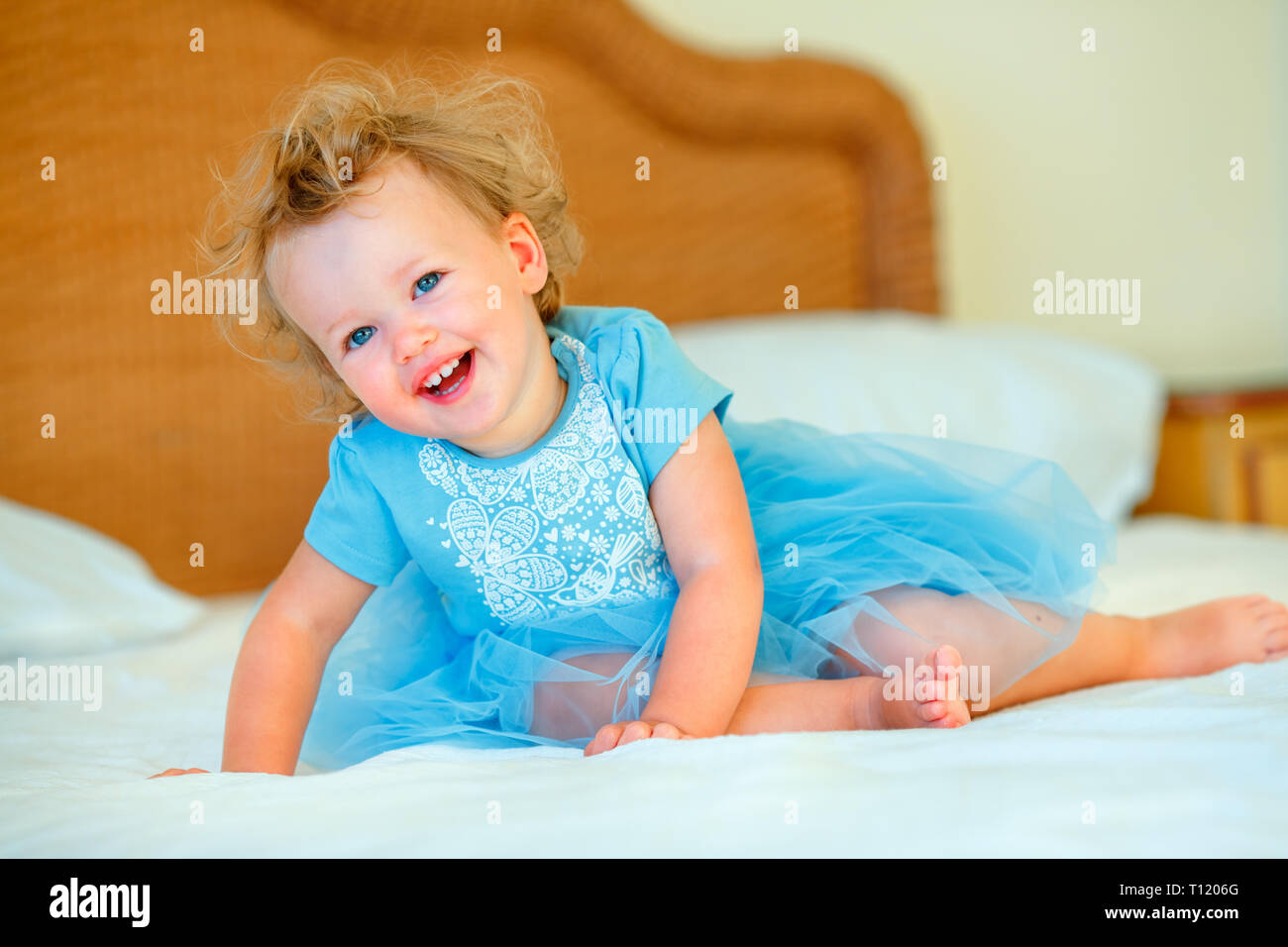 Lovely Happy Blonde Toddler Girl Sitting On A Bed In Bedroom Stock Photo Alamy