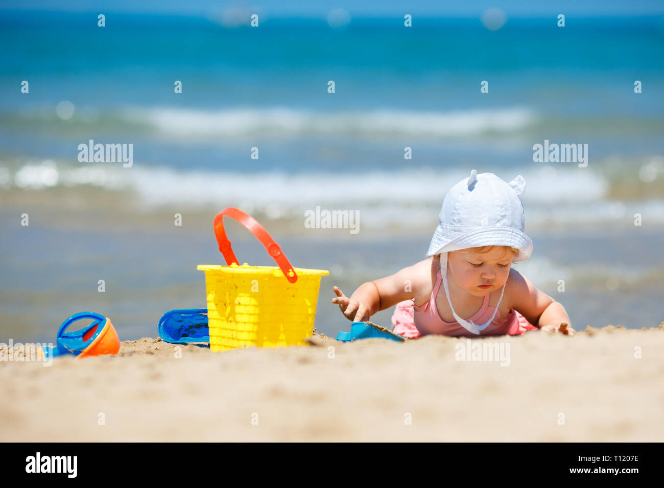 Child playing on tropical beach. Little girl digging sand at sea shore. Family summer vacation. Kids play with sand toys. Travel with young children Stock Photo