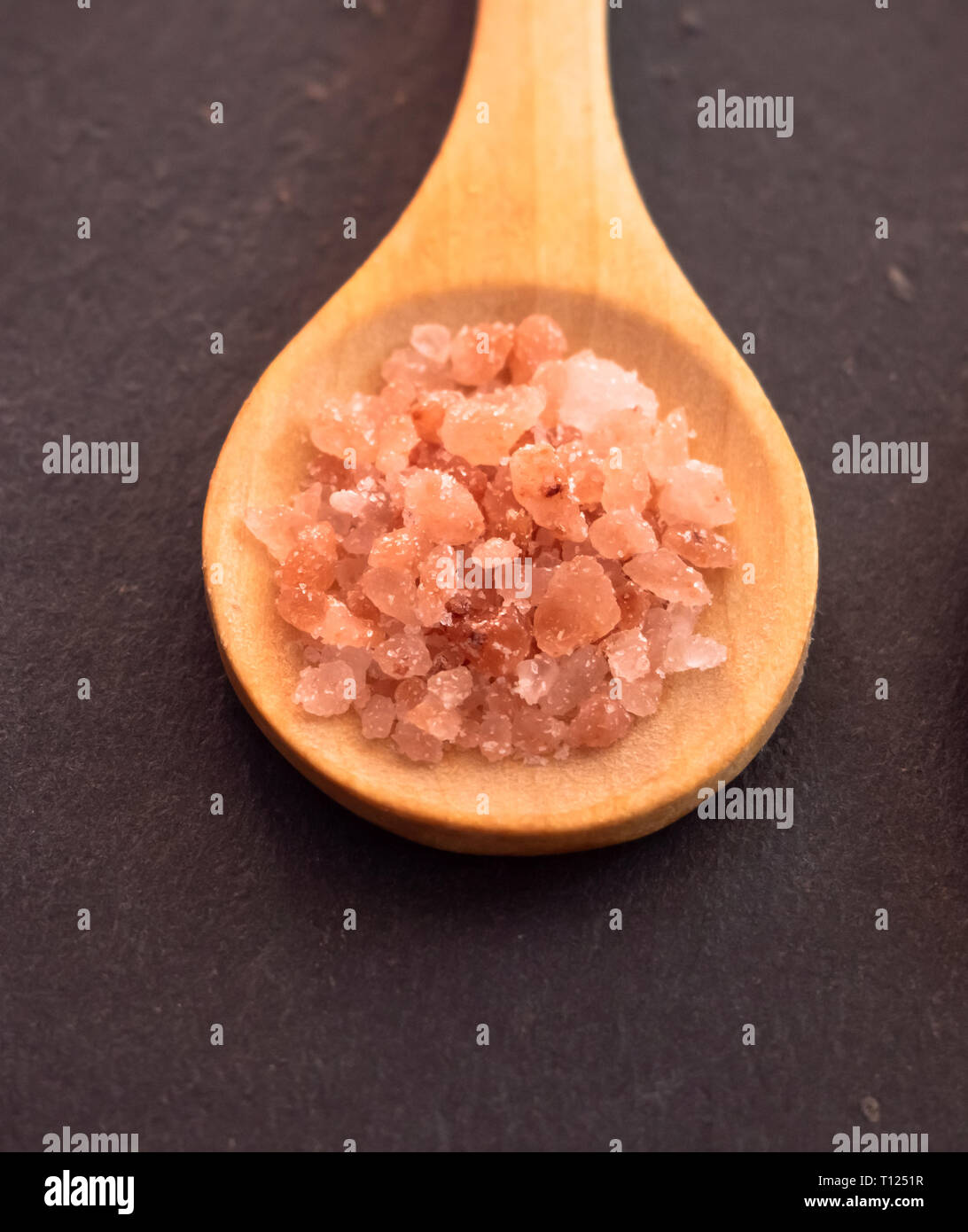 Wooden spoon with Himalayan pink salt on a slate plate Stock Photo