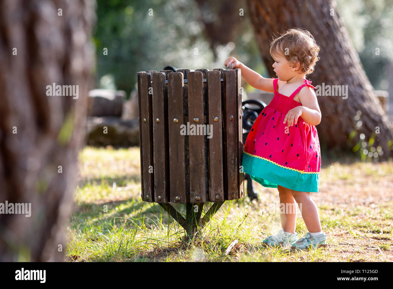 Sweet blond little baby girl throwing garbage into recycle bin Stock Photo