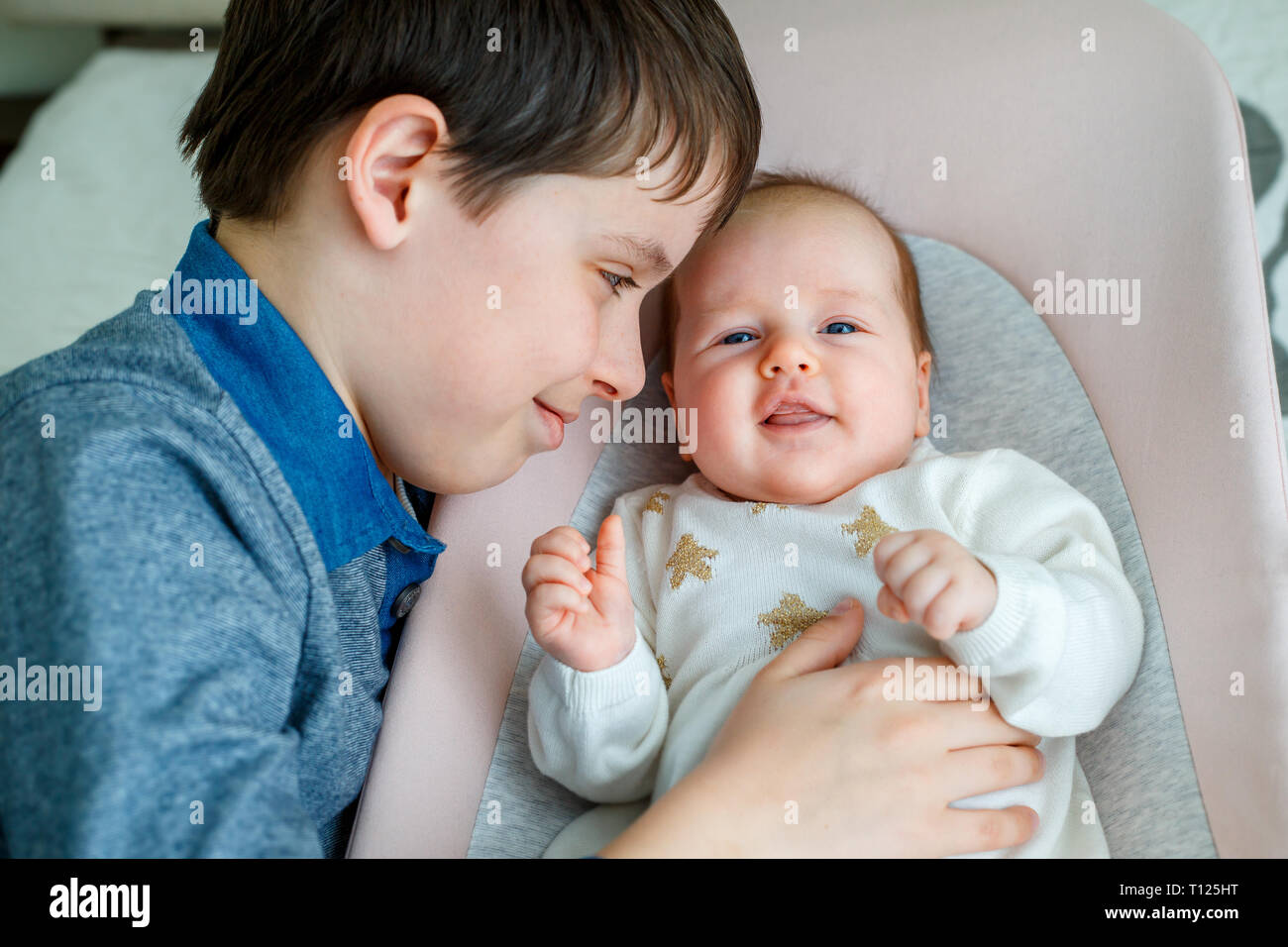 Big brother hugging his newborn baby girl at home Stock Photo
