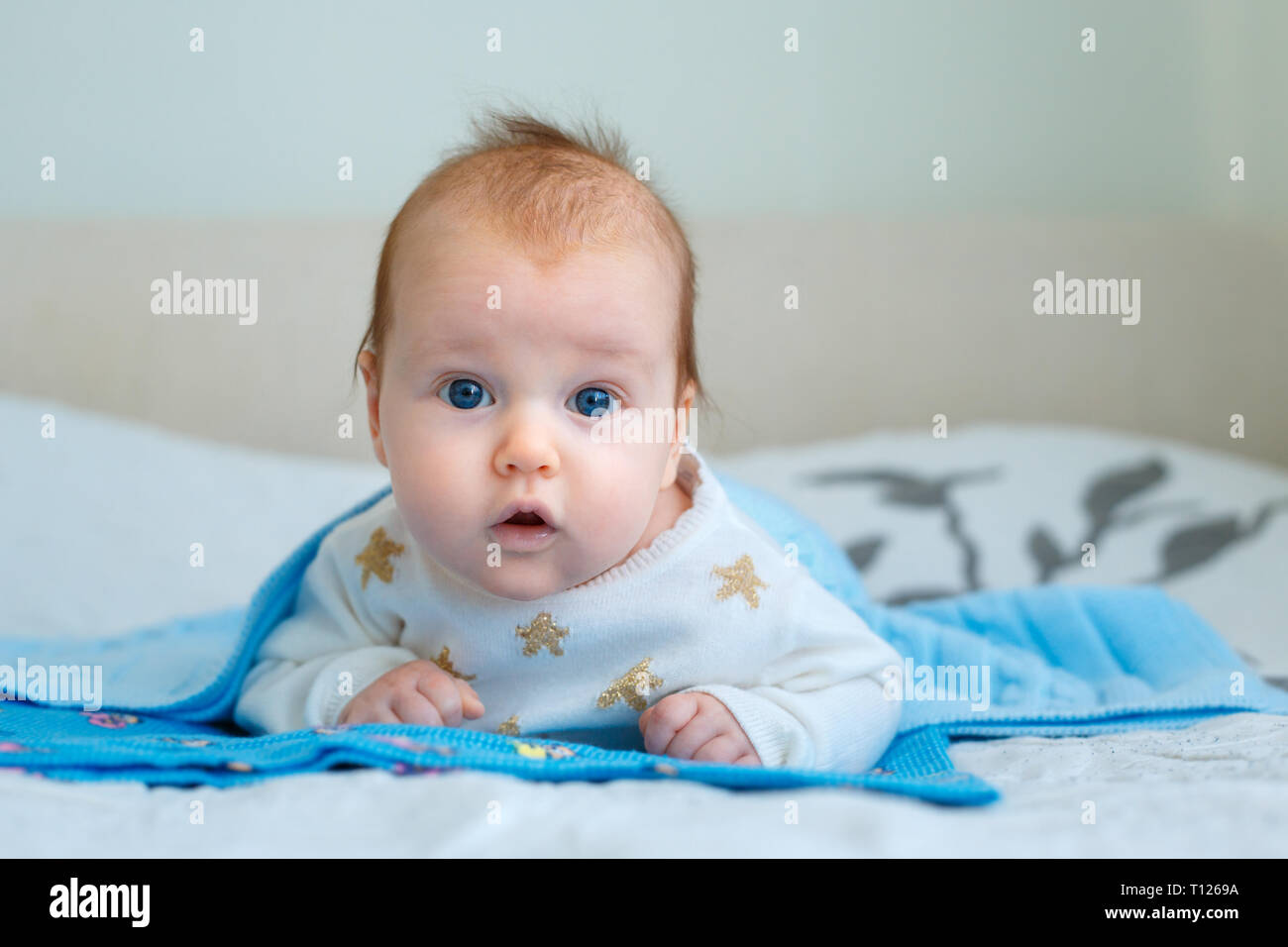 Portrait of a cute newborn baby lying on her stomach in bedroom Stock Photo