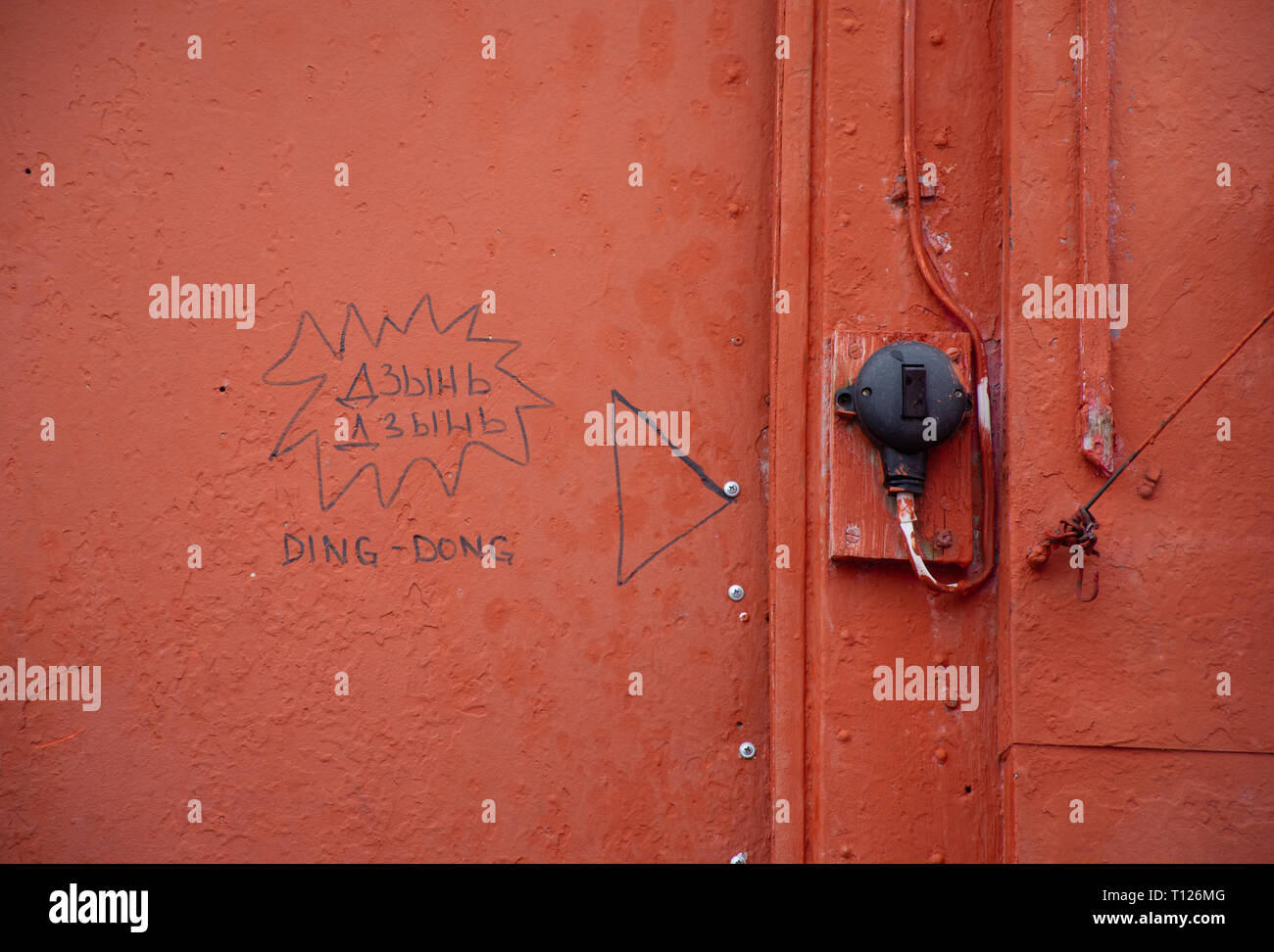 A door bell on a red building with ding dong written on the wall. Stock Photo