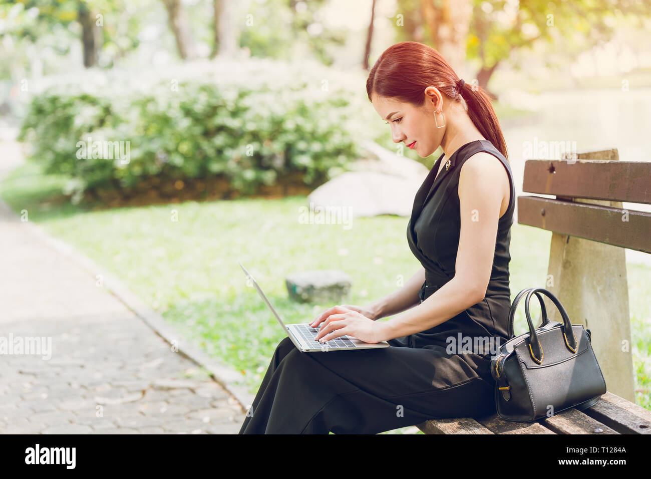beautiful business women using laptop to working in the park with happiness mood. Stock Photo