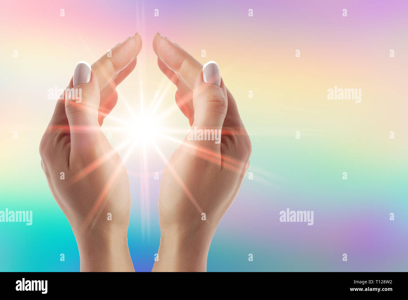 Healing hands with bright sunburst on rainbow background Stock Photo