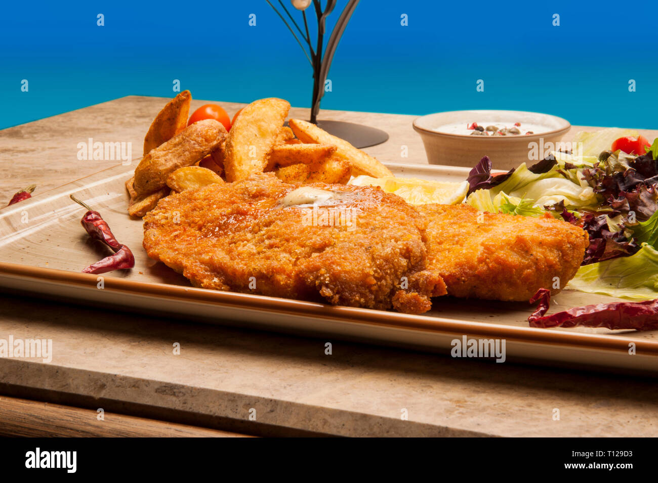 Chicken fritters prepared with corn flour, fried in oil, served with potatoes and sauces. Stock Photo