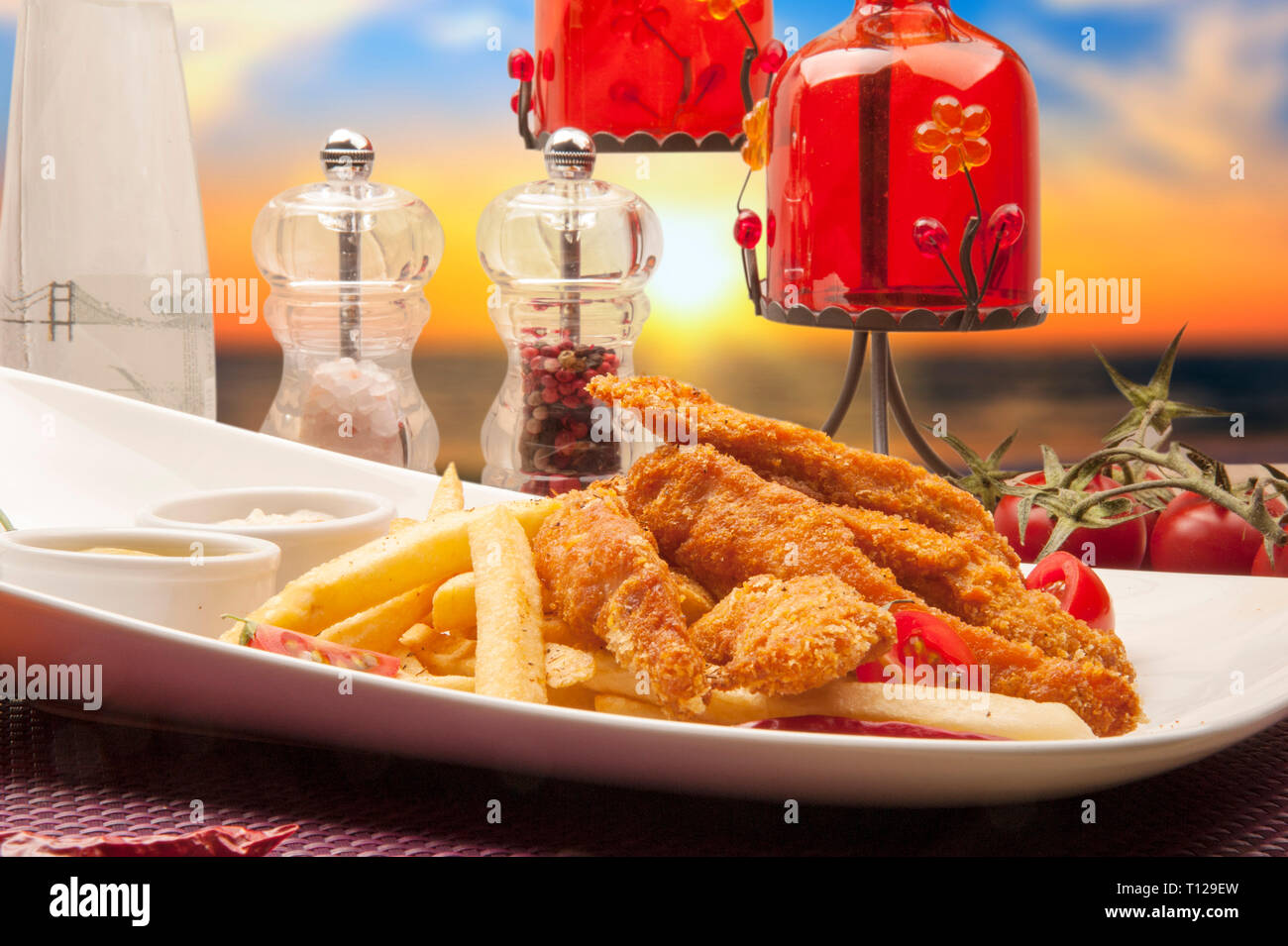 Chicken fritters prepared with corn flour, fried in oil, served with potatoes and sauces. Stock Photo