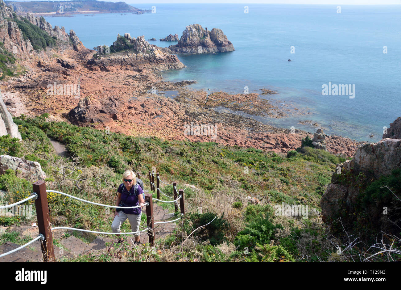 Lone Woman Hiker Climbing Steps out of Fiquet Bay on the Island of Jersey, Channel Isles, UK. Stock Photo