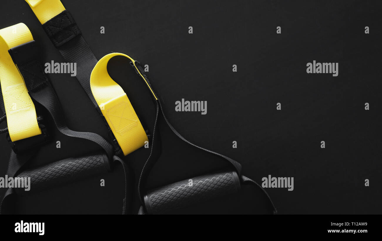 Black and yellow strap functional training equipment on grey background. Sport accessories