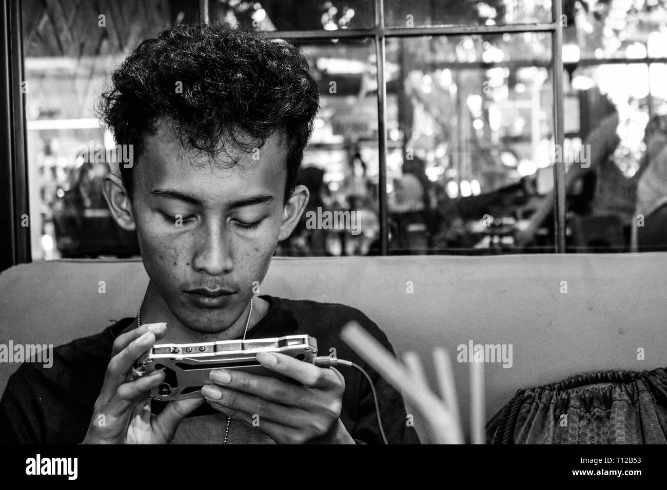 A teenager is playing a game on his cellphone Stock Photo