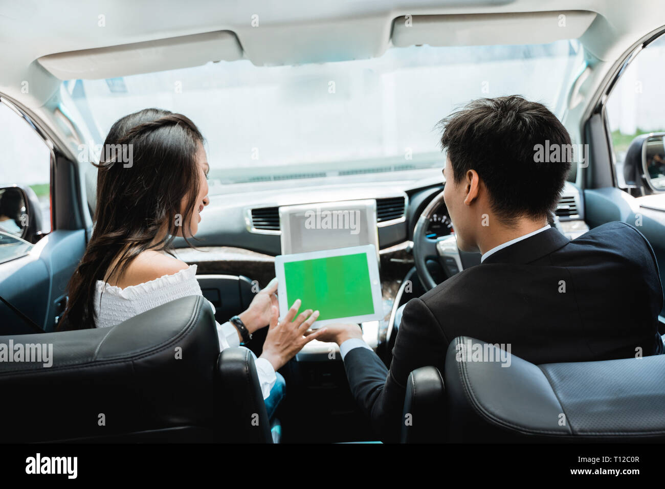 two couple using tablet together while driving a car Stock Photo