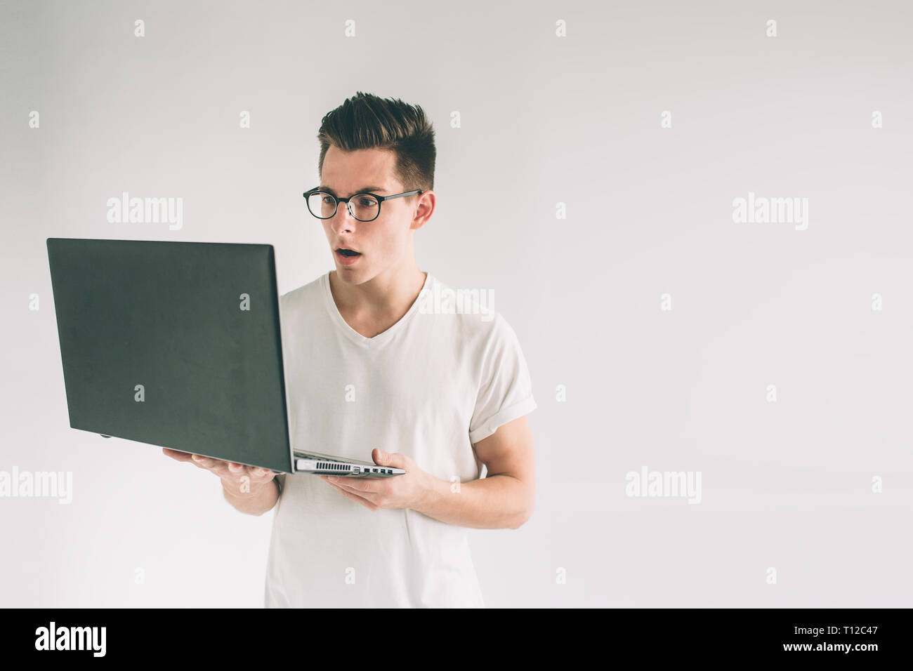 Man holding laptop computer isolated on gray. Nerd is wearing glasses ...