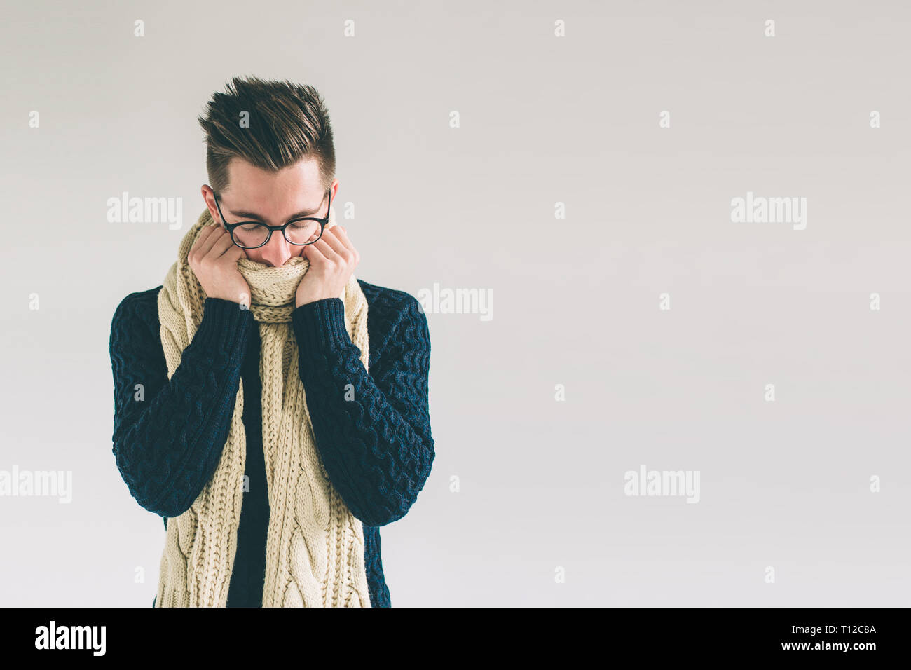 Young man in sweater feel cold over a white background Stock Photo