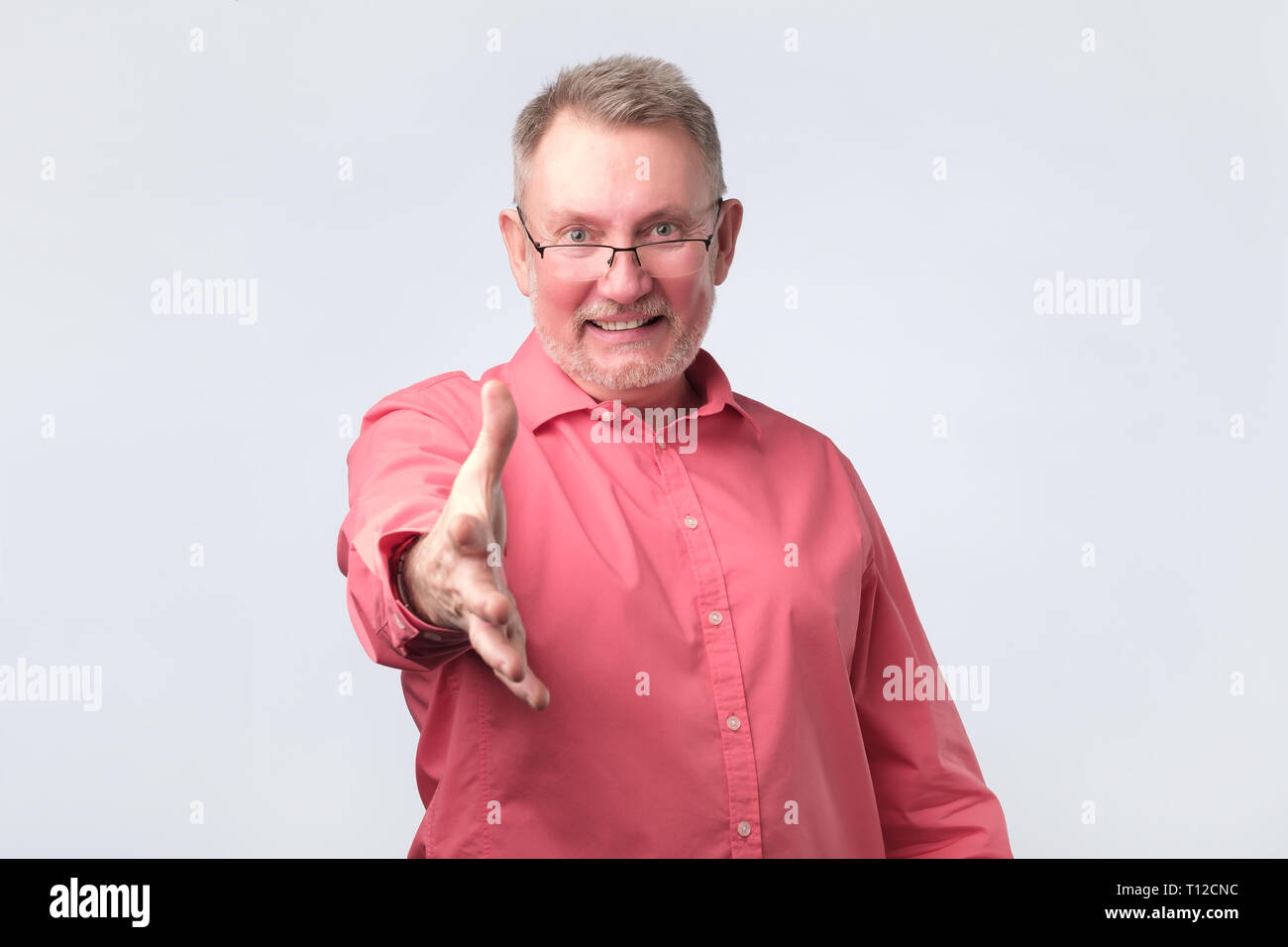 Handsome senior man in red shirt saying hello Stock Photo