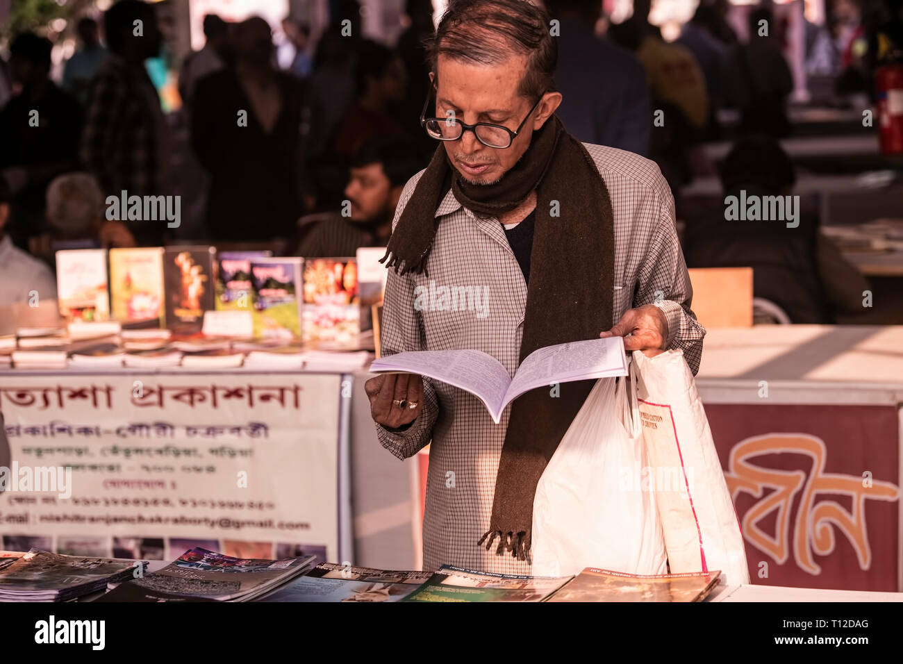 Kolkata,book,Fair,a mid-age,male book reader,reading,in,winter,afternoon,light, book,magzine stalls,in the ,background,Kolkata,India. Stock Photo