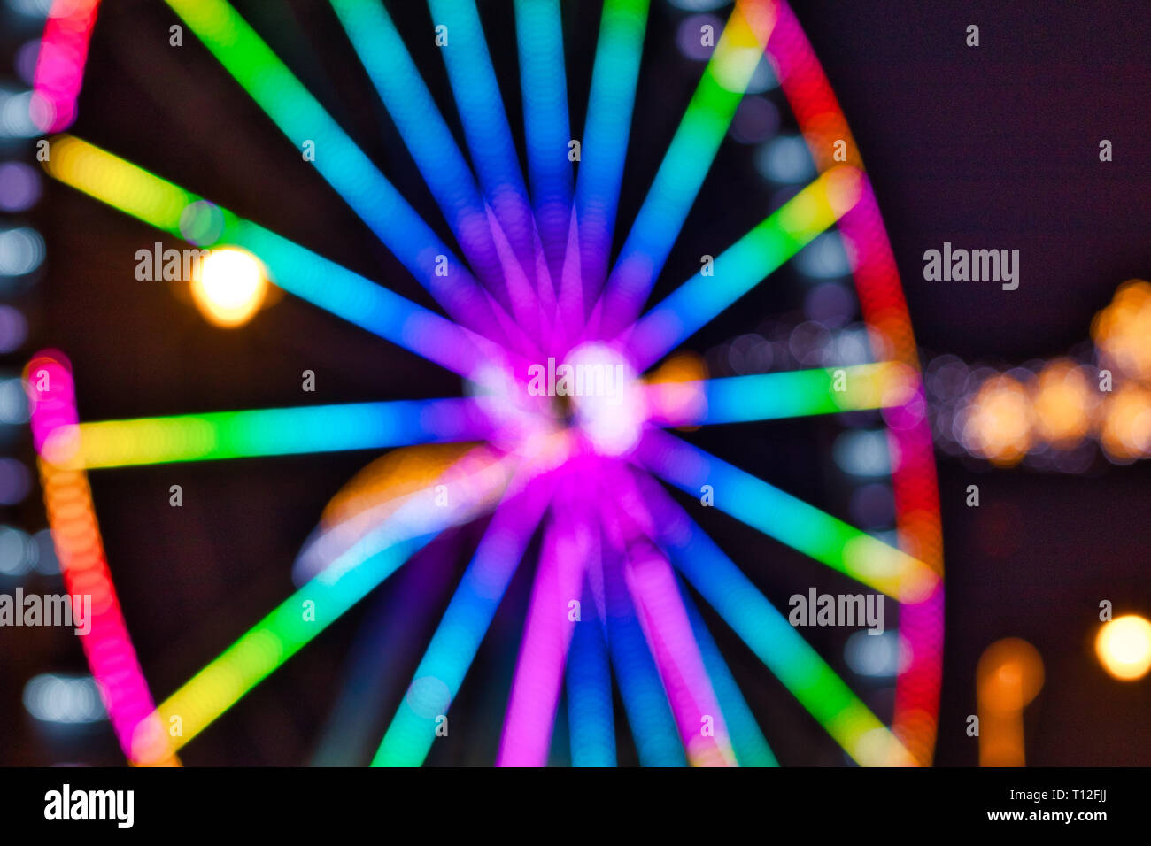 An out-of-focus shot of a colorful illuminated ferris wheel Stock Photo