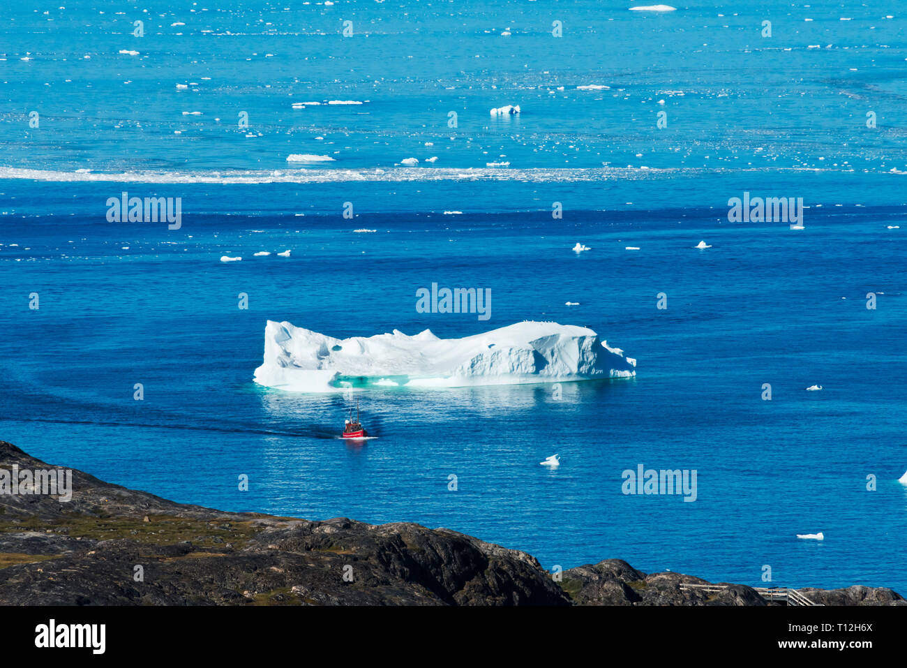 Ship sailing by floating iceberg in Ilulissat Icefjord, Greenland Stock Photo
