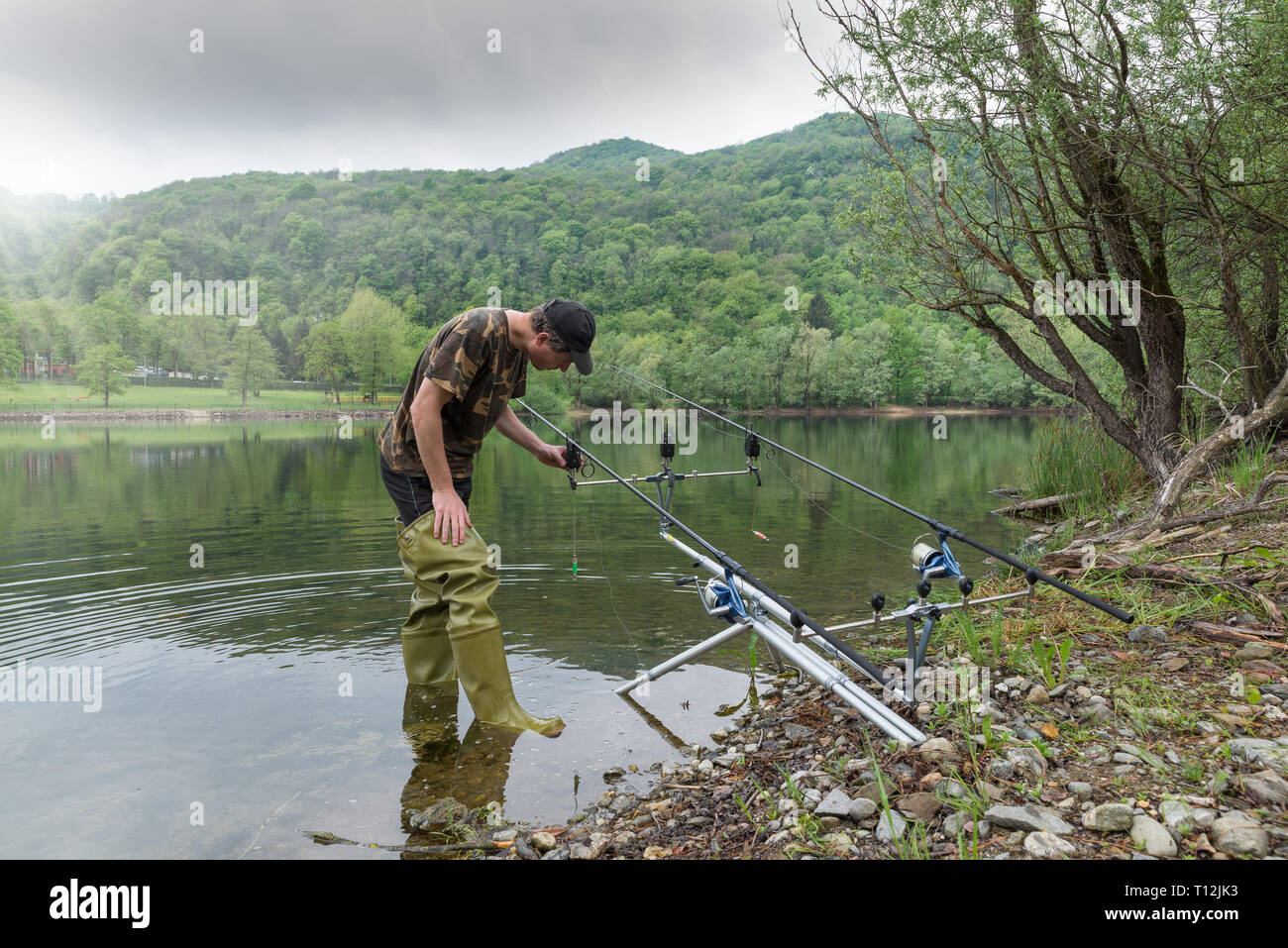 Fishing adventures, carp fishing. Fisherman with green rubber boots Stock Photo