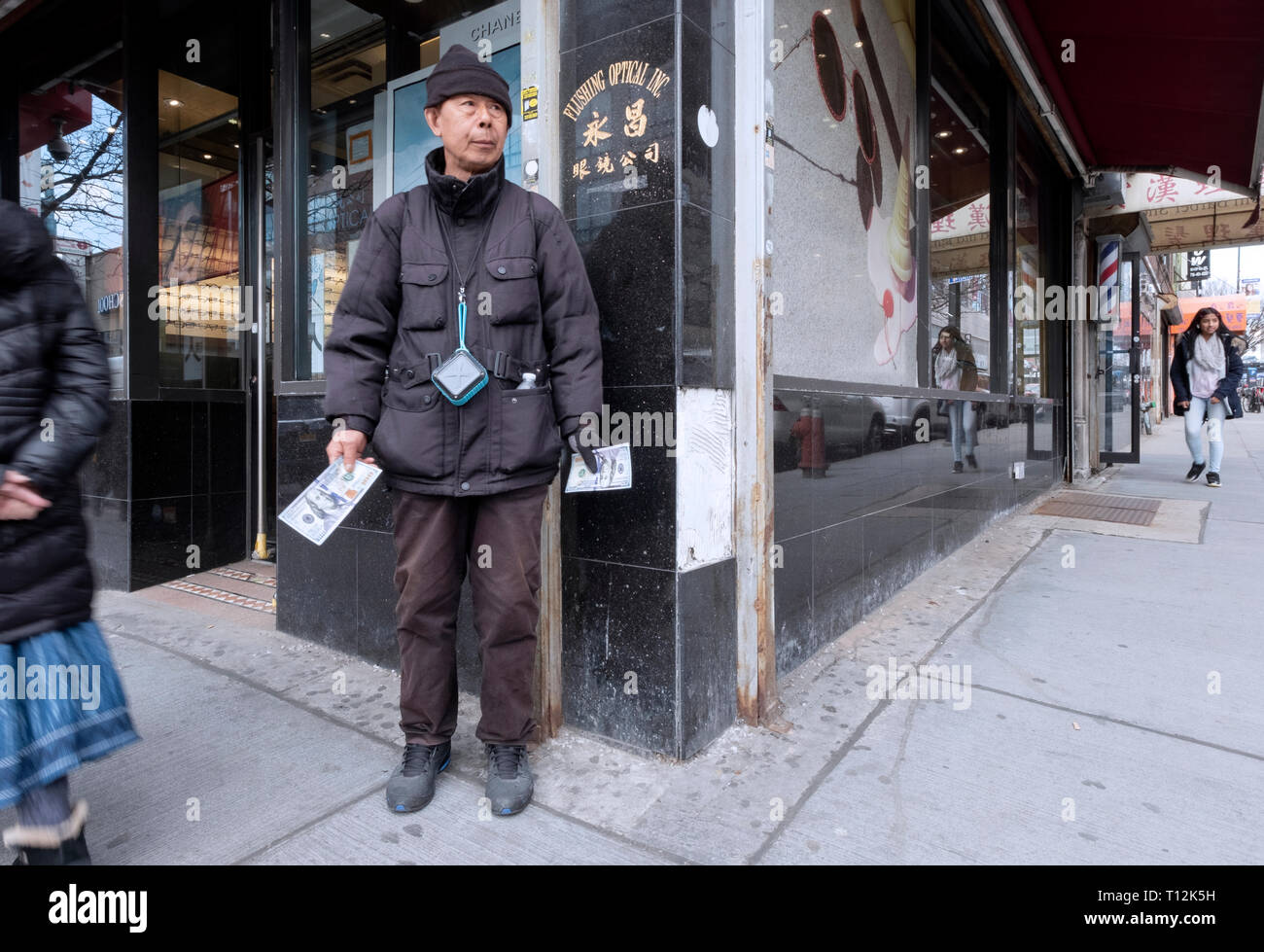 A worker in Chinatown hands out advertisements on oversized $100 bills in Flushing, Queens, New York City Stock Photo