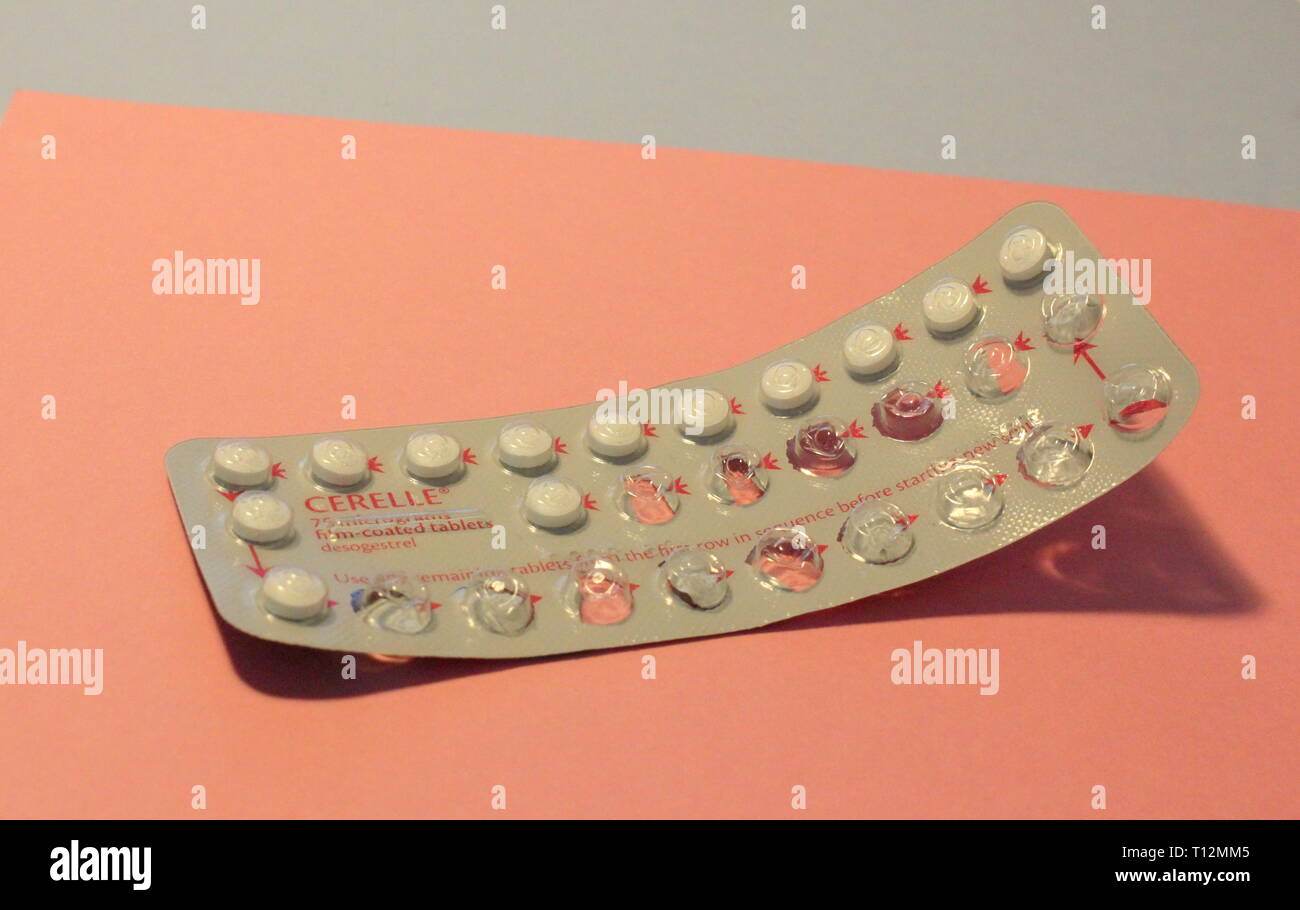 A close up photograph of a half-used contraceptive pill packet against a baby pink and baby blue color background. Feminine health and gender concept Stock Photo