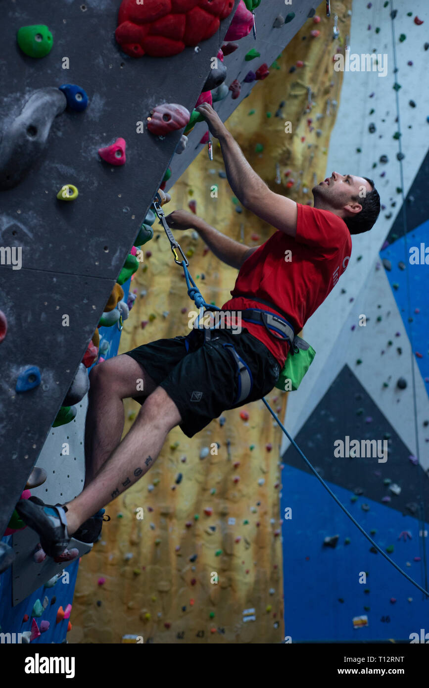 A rock climbing instructor climbs an indoor climbing wall Stock Photo ...