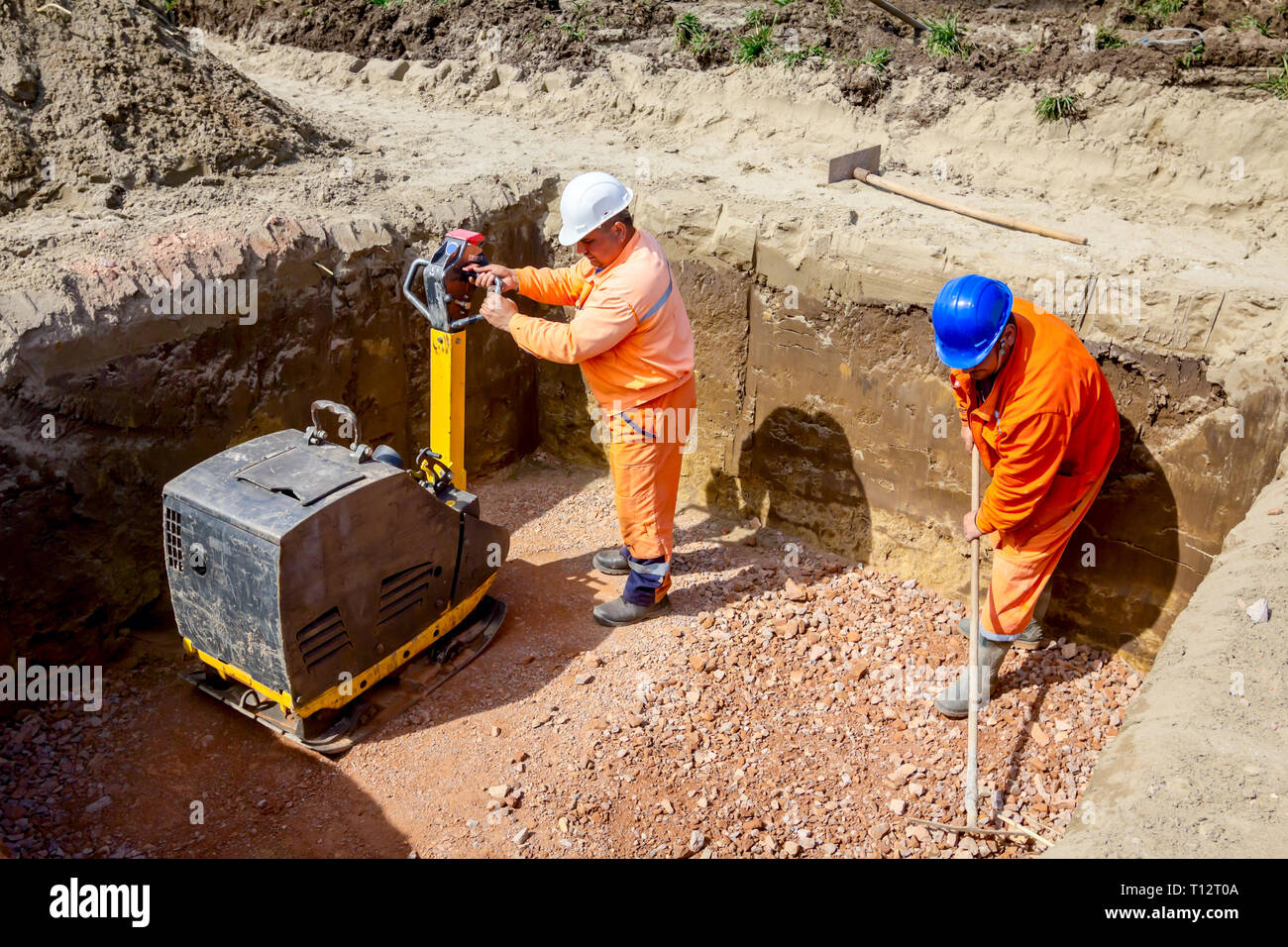 Workers are compacting gravel using vibration plate compactor machine