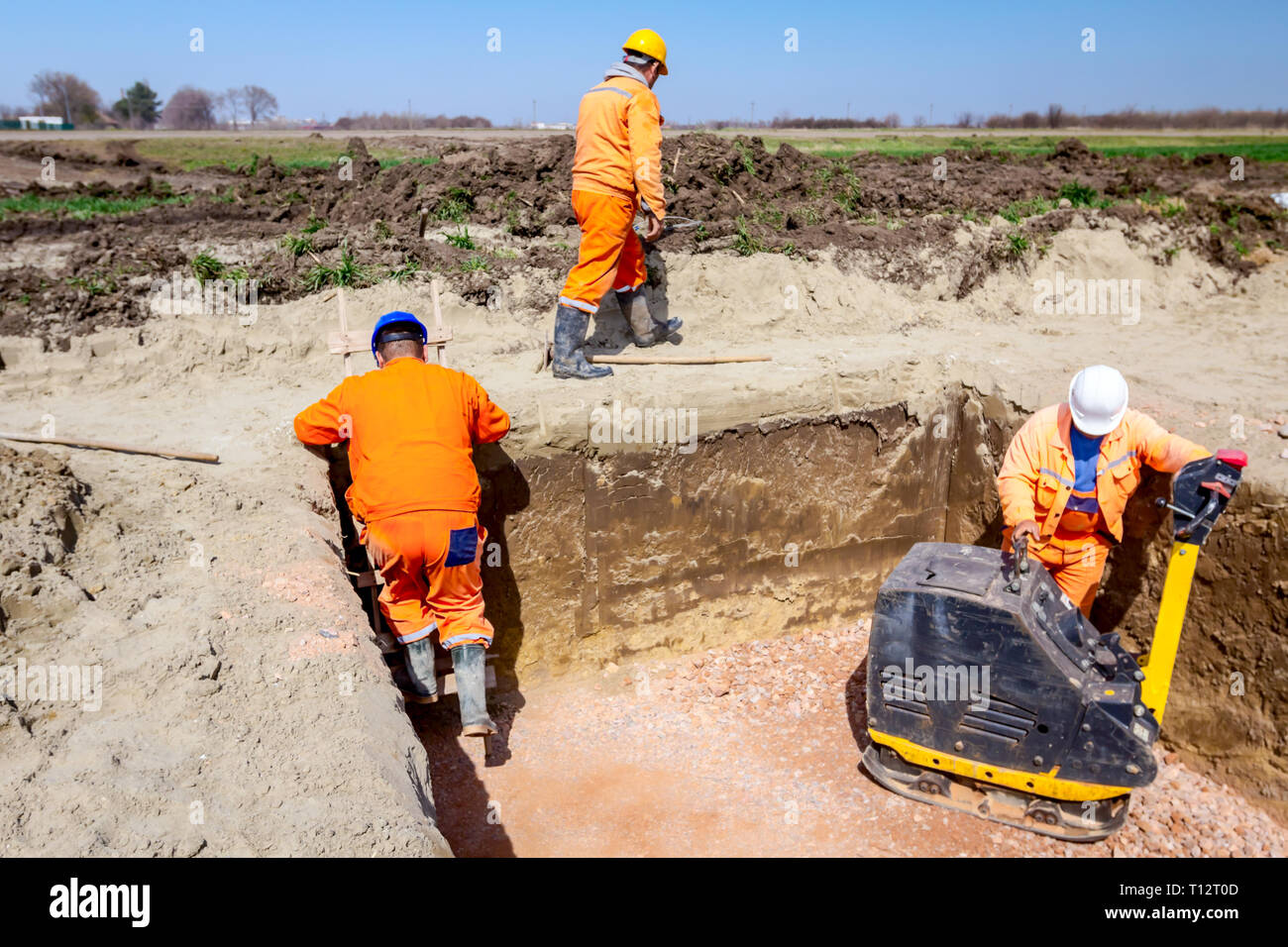 Worker is compacting gravel with vibration plate compactor machine in