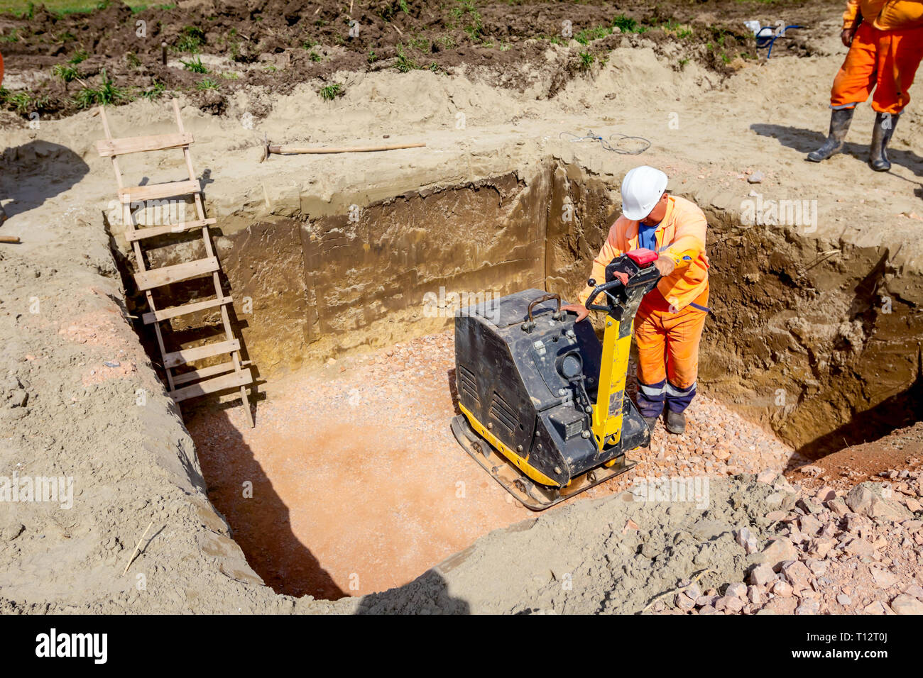Worker is compacting gravel with vibration plate compactor machine in