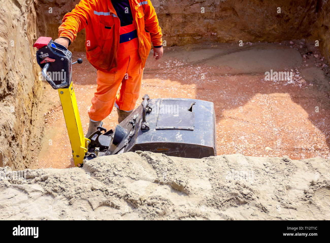 Worker is compacting gravel with vibration plate compactor machine in