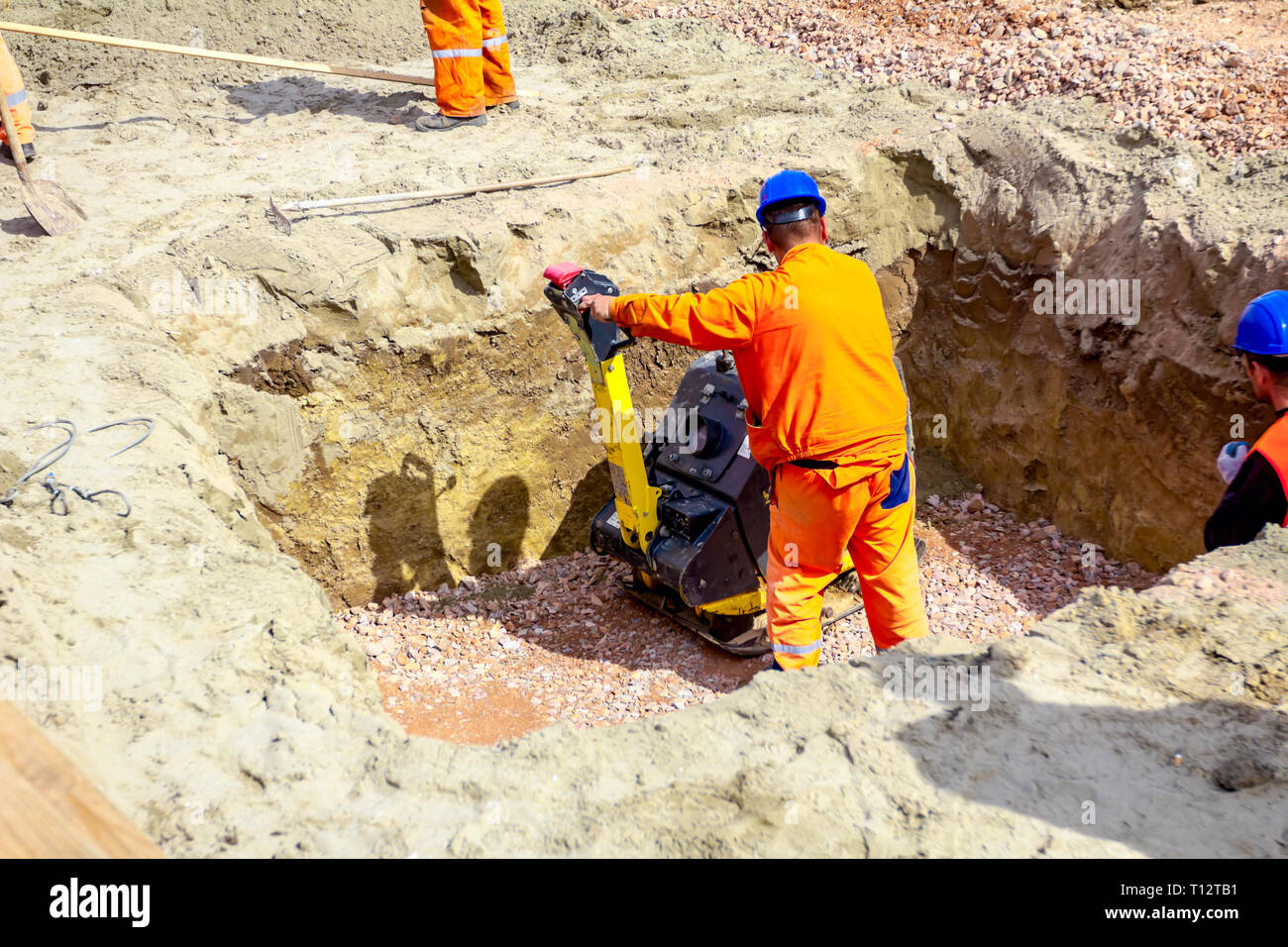 Worker is compacting gravel with vibration plate compactor machine in