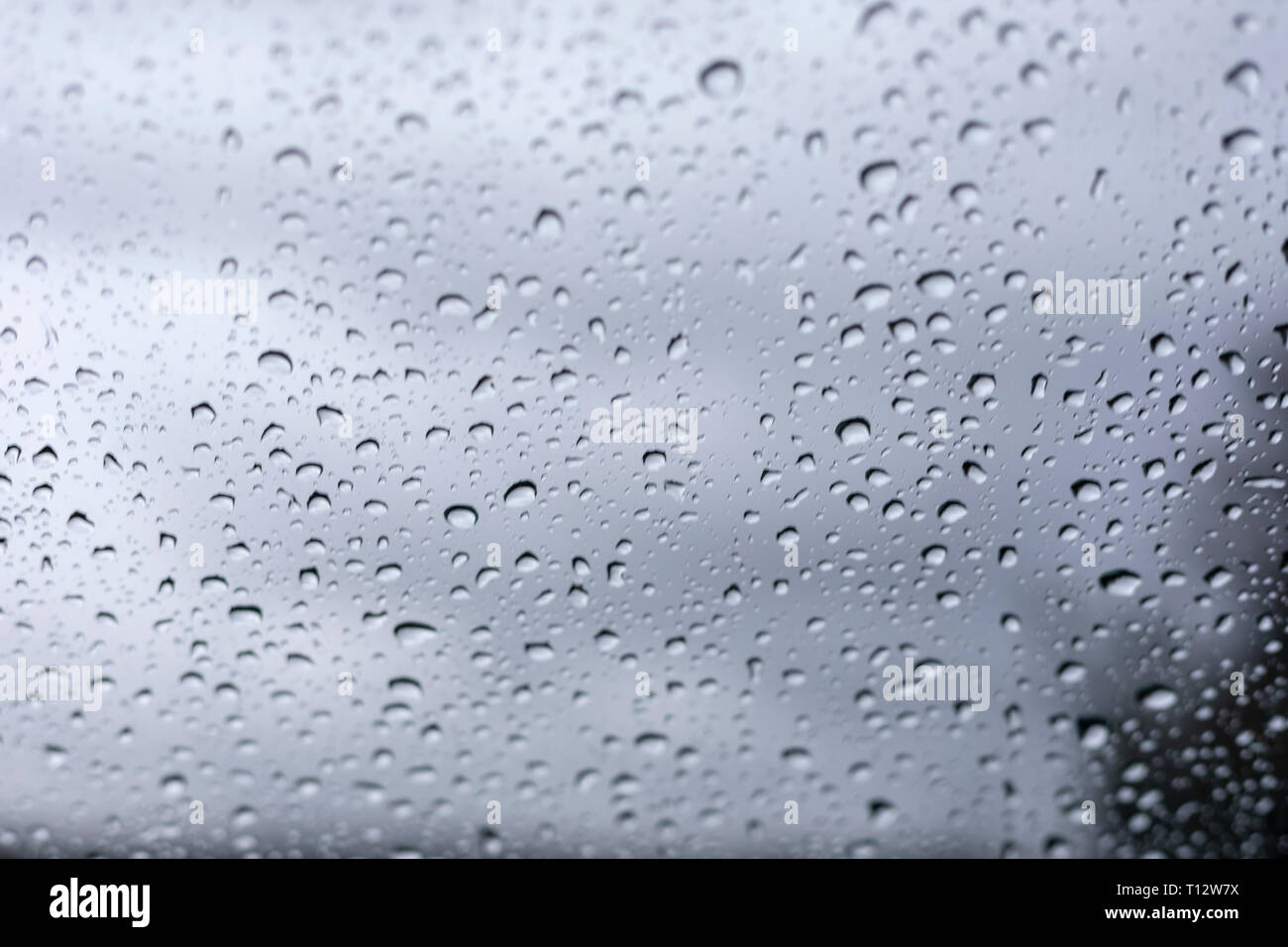 Rain drops on window glasses surface with cloudy background . Natural