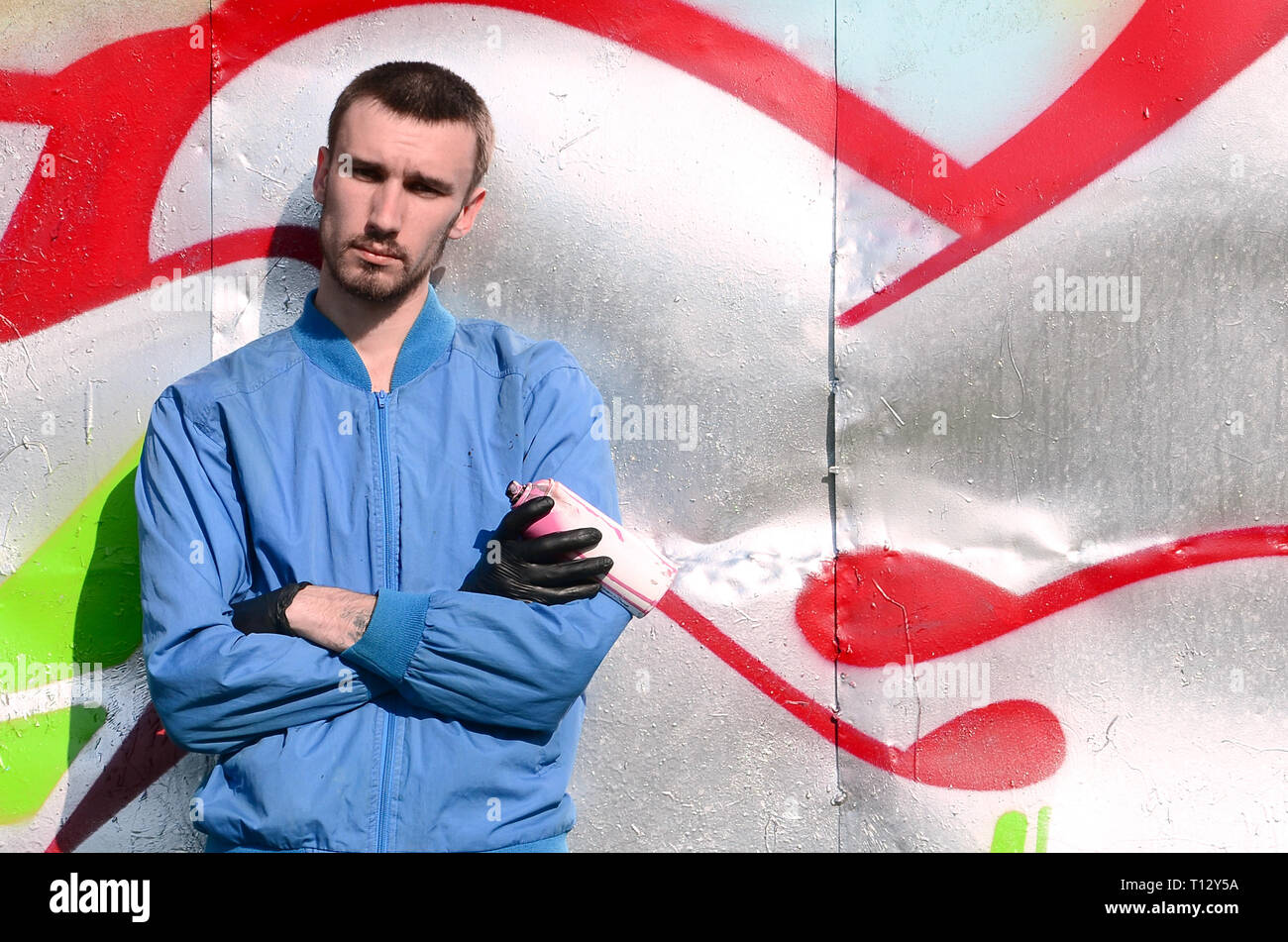 The graffiti artist with spray can poses against the background of a ...