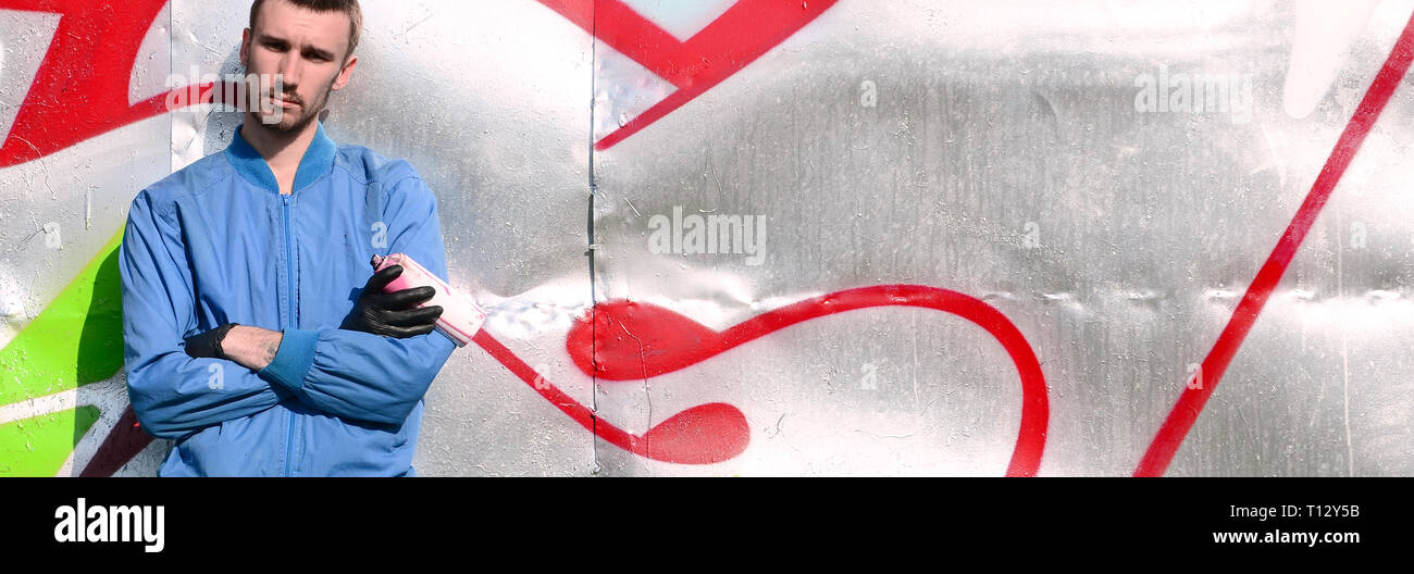 The graffiti artist with spray can poses against the background of a ...