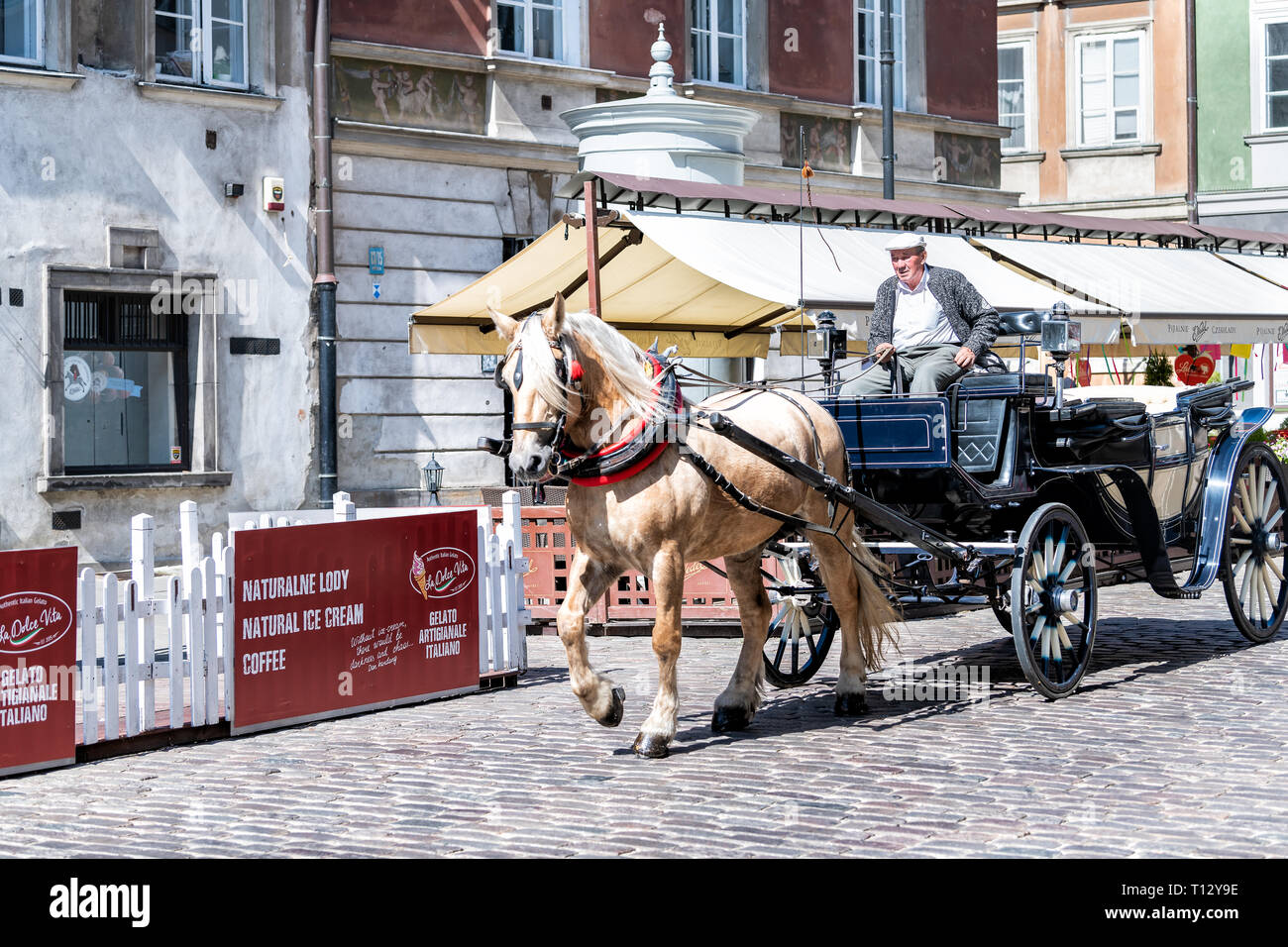 Warsaw, Poland - August 22, 2018: Historic buildings and horse carriage tour in old town during day and guide man Stock Photo
